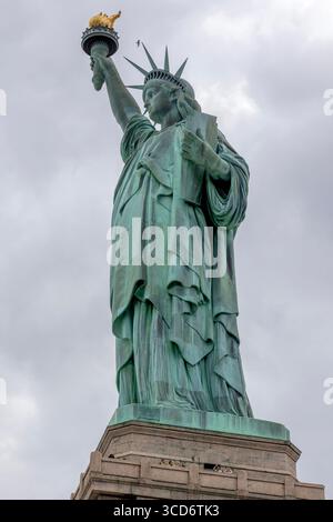 Blick auf die Freiheitsstatue auf Liberty Island, New York City, USA, an einem bewölkten Tag mit dramatischem Himmel und ikonischem Denkmal Stockfoto