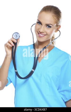 Eine hübsche junge Ärztin, die ihr Stethoskop hält, während sie auf weiß isoliert ist Stockfoto