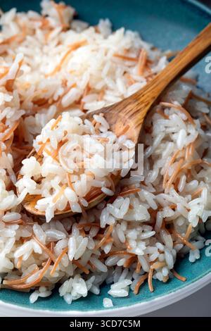 Nahaufnahme eines Tellers türkischer Reispilaw mit Vermicelli, serviert mit einem Holzlöffel. Stockfoto