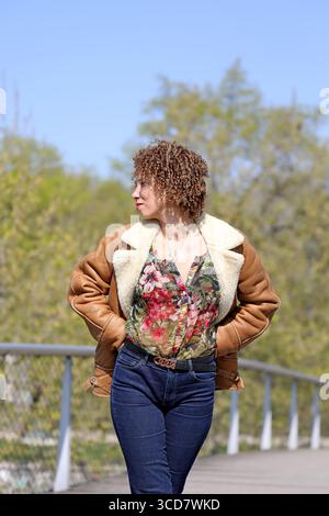 JUNGE FRAU MIT LOCKIGEM HAAR GENIESST FRÜHLING 2025 Stockfoto