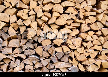 Ordentlich gestapeltes Brennholz mit satten Texturen und warmen Brauntönen. Die Nahaufnahme hebt die natürliche Variation der Holzmuster hervor. Sanfte Beleuchtungsverbesserung Stockfoto