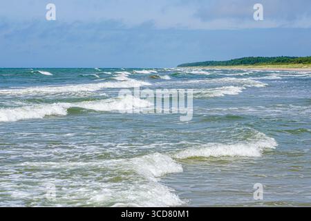 Sanfte Wellen der Ostsee krachen unter einem hellblauen Sommerhimmel sanft auf die Sandküste Stockfoto