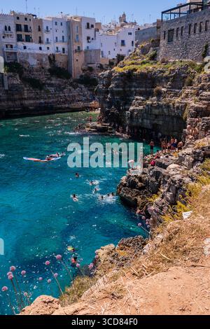 Menschen schwimmen und genießen einen Sommertag auf Pendma Chiatt (Pietra Piatta), Polignano a Mare, Apulien, Italien Stockfoto
