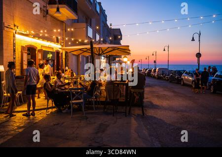 Gäste genießen das Abendessen bei Sonnenuntergang auf einer Restaurantterrasse in Polignano a Mare, Apulien, Italien Stockfoto