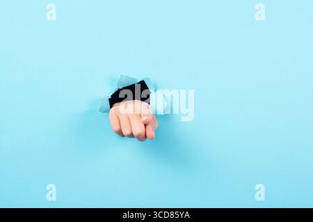 Finger Zeigt Nach Vorne, Kopierraum Für Werbung Und Marketing, Aufmerksamkeitsgeste, Loch In Blauem Papier Stockfoto