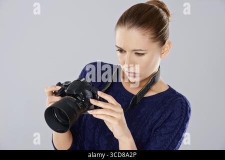 Schöne Fotografin mit einer professionellen digitalen dslr-Kamera, die ein Bild auf dem hinteren Sucher überprüft Stockfoto
