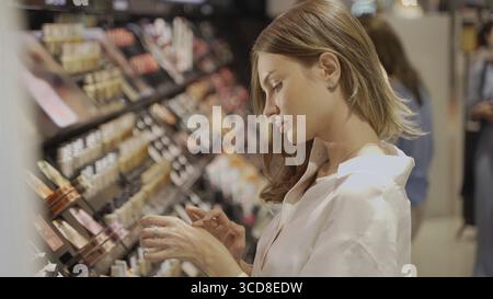 Ich probiere Make-up-Shades aus. Elegante junge Frau, die Augenschatten und Mascara im Einzelhandel testet Stockfoto