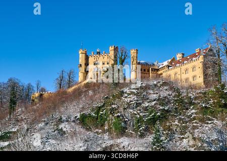 Ein majestätisches gelbes Schloss in der Nähe des berühmten Schlosses Neuschwanstein, auf einem Hügel mit malerischem Blick auf die umliegenden Berge. Die Stockfoto
