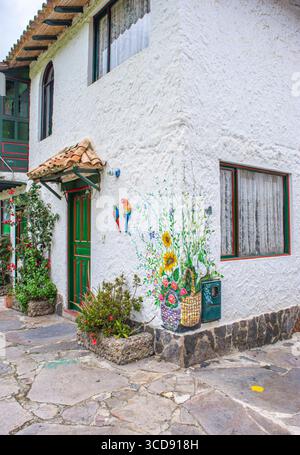 Ein malerisches Kolonialhaus in Pueblito Boyacense, Duitama, mit lebendigen Wandgemälden, farbenfrohen Blumen und einem einladenden Ambiente. Stockfoto