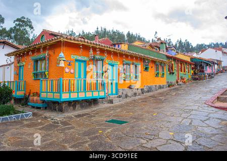 Pulsierende Kolonialarchitektur in Pueblito Boyacense, Duitama, Kolumbien, mit leuchtenden orangen und grünen Häusern in einer bezaubernden Kopfsteinpflasterstraße. Stockfoto