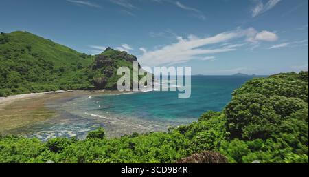 Blick von der Drohne auf die atemberaubende Strandlandschaft der Insel Kuata in Fidschi mit üppiger tropischer Vegetation, die die Hügel bedeckt, türkisfarbenem Wasser und einem wunderschönen sonnigen Tag. Drohnenflug Stockfoto