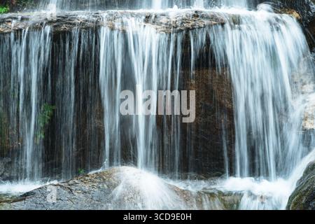 Seidig fließendes Wasser eines kleinen Wasserfalls über Felsen Stockfoto