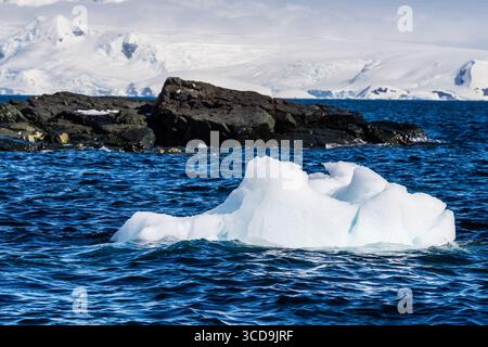 Eine beschauliche antarktische Landschaft in der Nähe des Hafens Mikkelsen auf Trinity Island, mit starken Reflexen, zerklüfteten Bergen und beeindruckenden Eisbergen Stockfoto