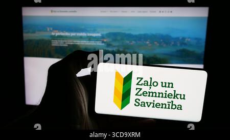 Deutschland. Juli 2025. In dieser Fotoabbildung hält eine Person ein Mobiltelefon mit dem Logo der Partei Zalo un Zemnieku Savieniba (ZZS) auf dem Bildschirm vor der Webseite. (Foto von Timon Schneider/SOPA Images/SIPA USA) *** ausschließlich für redaktionelle Nachrichten *** Credit: SIPA USA/Alamy Live News Stockfoto