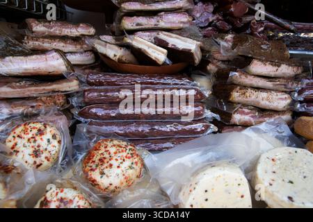 Nahaufnahme verschiedener Räucherfleisch, Speck, Würstchen und gewürzter Käse in Vakuumverpackungen, die auf einer Markttheke ausgestellt werden. Traditionelle Delikatessenprodukte f Stockfoto