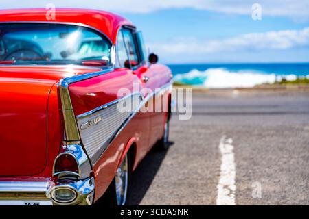 Kräftig rot 1957 Chevy Bel Air parkte im Sonnenlicht und präsentierte sein Chrom und seine Kurven. Eine zeitlose amerikanische Autokultur mit Nostalgie und Vintage Stockfoto
