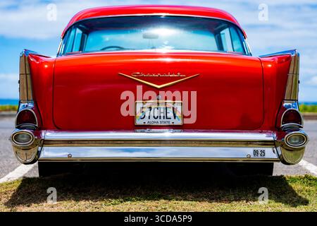 Kräftig rot 1957 Chevy Bel Air parkte im Sonnenlicht und präsentierte sein Chrom und seine Kurven. Eine zeitlose amerikanische Autokultur mit Nostalgie und Vintage Stockfoto