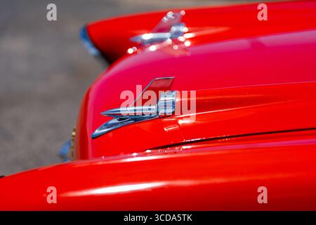 Kräftig rot 1957 Chevy Bel Air parkte im Sonnenlicht und präsentierte sein Chrom und seine Kurven. Eine zeitlose amerikanische Autokultur mit Nostalgie und Vintage Stockfoto