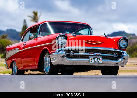 Kräftig rot 1957 Chevy Bel Air parkte im Sonnenlicht und präsentierte sein Chrom und seine Kurven. Eine zeitlose amerikanische Autokultur mit Nostalgie und Vintage Stockfoto