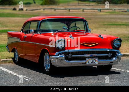 Kräftig rot 1957 Chevy Bel Air parkte im Sonnenlicht und präsentierte sein Chrom und seine Kurven. Eine zeitlose amerikanische Autokultur mit Nostalgie und Vintage Stockfoto