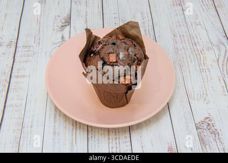 Klassische Buttermuffins mit Schokoladenfrosting und knusprigen Waffelstücken Stockfoto