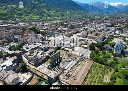 Die Ruinen des römischen Theaters stehen stolz inmitten der modernen Stadt, umgeben von den majestätischen Alpen, Aosta, Aostatal, Italien. Stockfoto