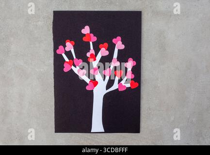 Ein Baum aus Herzen ist auf schwarzem Hintergrund. Der Baum besteht aus Papierherzen und ist eine kreative Art, Liebe auszudrücken Stockfoto