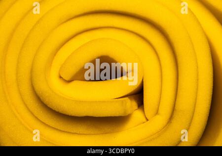 Gelber Schaumgummi zu einer Rolle verdreht, Nahaufnahme. Stockfoto