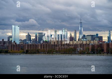 Blick auf die Skyline von Downtown Manhattan, die durch den gedämpften Himmel durchdringt, wo moderne Wolkenkratzer und ältere Gebäude im Kontrast stehen, die sich im ruhigen Wasser spiegeln, New York, New York, USA. Stockfoto