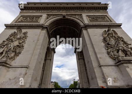 Blick auf den imposanten Arc de Triomphe, einen monumentalen Bogen mit komplizierten Details vor dem Hintergrund eines bewölkten Himmels, Paris, Île-de-France, Fr. Stockfoto