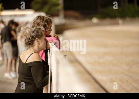 Padua, italien 18. juli 2025, Mutter und Tochter genießen einen Tag bei den Rennen, lehnen sich auf den Zaun und beobachten die Pferde Stockfoto