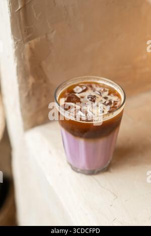 Ein erfrischendes Glas Lavendelkaffee in minimalistischer Atmosphäre. Kalte Brauerei mit blumigem Aroma, weichen Pastelltönen, gemütlich und modern. Stockfoto