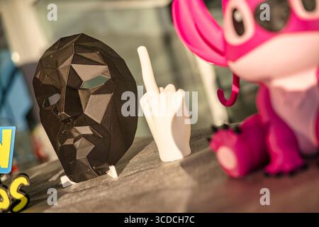 Rom, italien 18. juli 2025, Maske mit niedrigem Poly, offensiver Handbewegung und pinke Stich-Figur zeigen die Vielfalt des 3D-Drucks Stockfoto