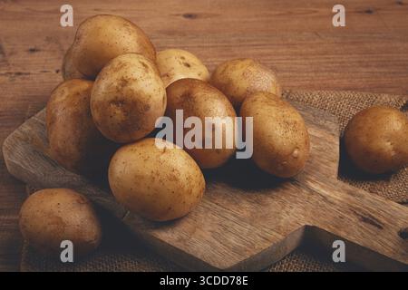 Rohe Kartoffeln, verstreut auf einem Schneidebrett, Nahaufnahme, keine Leute Stockfoto