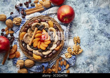 Zusammensetzung von getrockneten Früchten und Nüssen in einer kleinen Korbschale auf einem Steintisch. Sortiment Contais Mandeln, Walnüsse, Aprikosen, Pflaumen, Feigen, Datumsangaben, Stockfoto