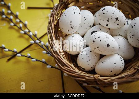 Ganze Hühnereier in braunem Korb. Das Konzept der Osterferien. Gelber Holzhintergrund. Flache Lage, Draufsicht Stockfoto