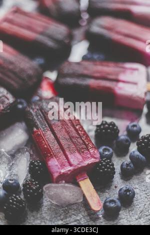 Hausgemachte brombeer- und Sahneeis oder Eis mit gefrorenen Beeren auf einem Tablett aus schwarzem Schiefer vor dunklem Hintergrund. Draufsicht, flach Stockfoto