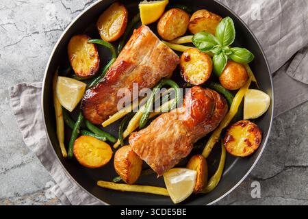 Zitronenknoblauch Schweinebraten mit französischen Bohnen und neuen Kartoffeln in einer Pfanne auf dem Tisch. Horizontale Draufsicht von oben Stockfoto