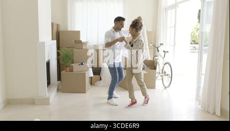 Glückliches junges Paar feiert beweglichen Zuhause tanzen zusammen im Wohnzimmer umgeben von Kartons Stockfoto