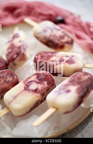 Hausgemachte frische Sahne- und Kirschkreme auf weißer Keramikplatte mit Früchten und Textilien. Draufsicht, flach Stockfoto