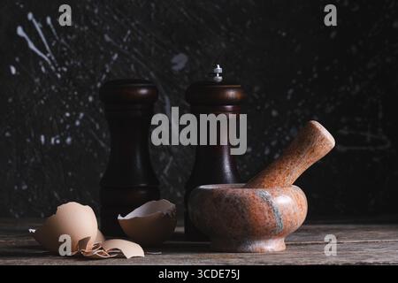 Pfeffermühle, Mörtel, Salzstreuer und Eierschalen auf Holztisch Stockfoto