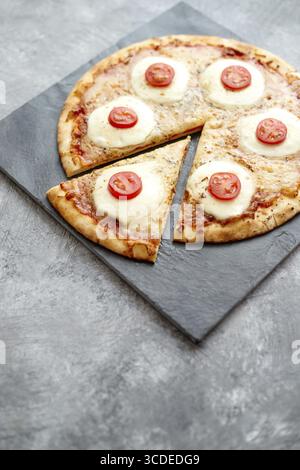 Hausgemachte Pizza mit Tomaten, Mozzarella. Draufsicht mit Kopierraum auf Tisch mit dunklem Stein Stockfoto