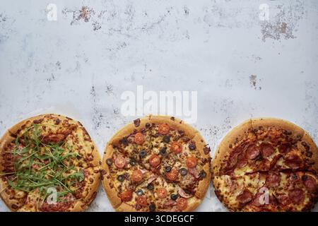 Drei verschiedene Arten von Pizzen. In einer Reihe auf weißem rostigem Tisch platziert. Ansicht von oben mit einem Leerzeichen für Ihren Text Stockfoto