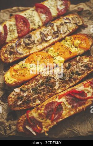 Komposition von heißen, leckeren gebackenen Sandwiches mit verschiedenen Belägen. Käse, Thunfisch, Mozarella, Oliven, Gewürze, Zucchini, Tomaten. Köstliches hausgemachtes Essen. T Stockfoto