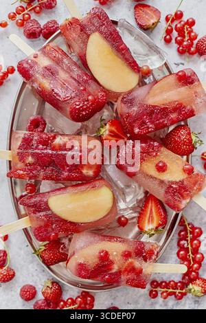 Hausgemachte Himbeeren, Erdbeeren, Apfel und Johannisbeeren-Eis auf Metallteller mit Eis, verschiedene Beeren. Gesundes Sommernahrungskonzept. Draufsicht, flach Stockfoto