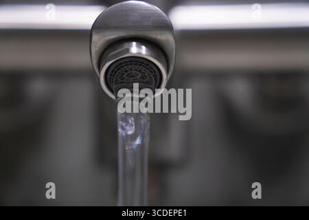 Sauberes Wasser aus einem Belüfter aus gebürstetem Metall mit Wasserhahn in einem modernen Badezimmer, das eine Atmosphäre der Hygiene und Erfrischung schafft und gleichzeitig verbessert Stockfoto