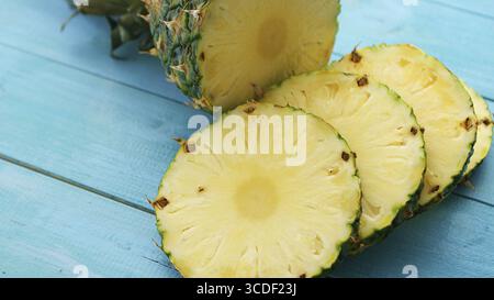 Von oben geschossen von geschnittenen Scheiben von frischem Gelb Ananas serviert auf blau gefärbten hellen Holz- Tabelle Stockfoto