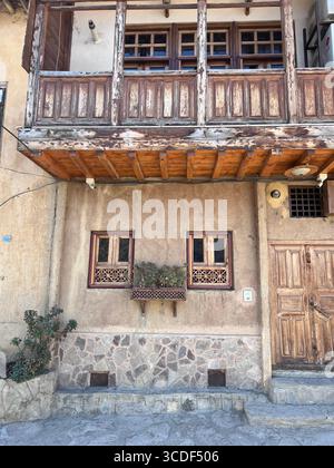 Rustikale Fassade mit Holzbalkon und Steinfuß in Masuleh, einem UNESCO-Weltkulturerbe-Dorf im Iran. Stockfoto