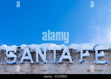 Frischer Schnee bedeckt die berühmten Santa Fe Buchstaben am Bahnhof im Railyard District in New Mexico unter einem hellen Winterhimmel. Stockfoto