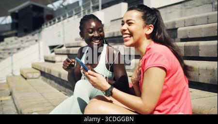 Fitness, Ohrhörer und Freundinnen im Freien mit Telefon zum Musikhören, Networking oder soziale Medien. Lachen, Sport und weibliche Athleten Stockfoto